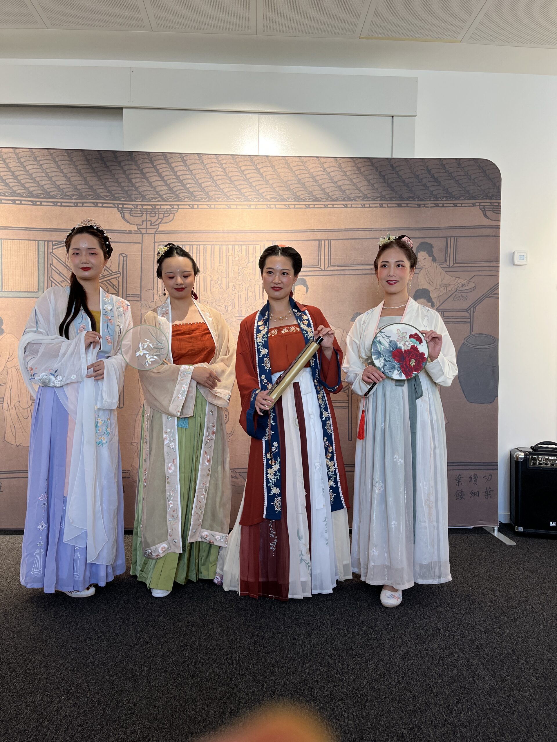 Four presenters wearing colourful Hanfu and holding traditional fans